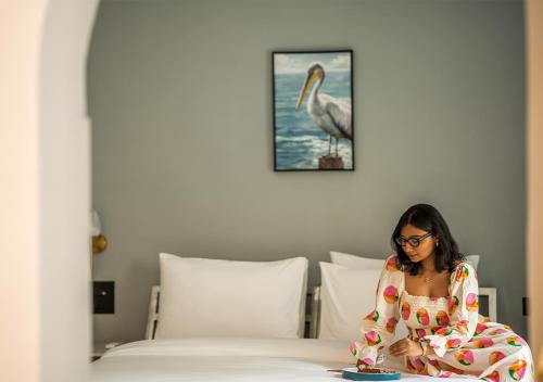 a woman sitting on a bed with a plate at Moustache Udaipur Verandah in Udaipur