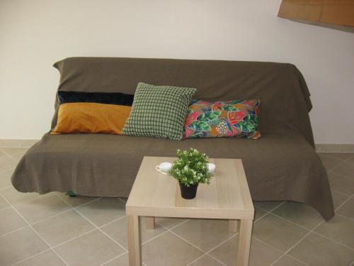 un sofá con almohadas y una mesa con una planta en T 2 avec velux au 1er étage de 34 m2, en La Londe-les-Maures