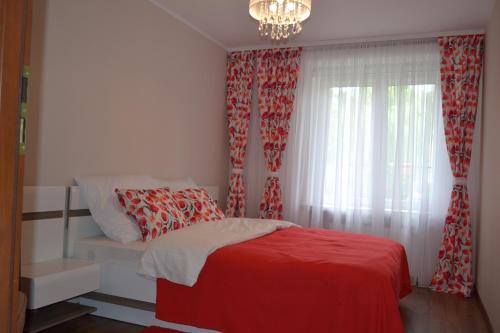グダニスクにあるApartament Groblaのベッドルーム1室(赤いカーテンと窓付きのベッド1台付)