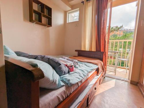 een slaapkamer met een bed en een raam met een balkon bij Skies Condo unit in Moldex Residences Baguio in Baguio