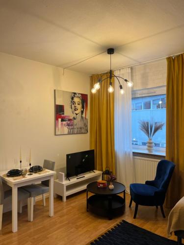 a living room with a tv and a blue chair at Noah Longstay Borås in Borås