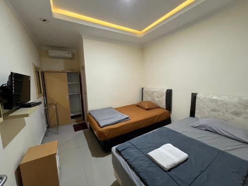 a small room with two beds and a television at Omah Belimbing RedPartner near ABM Malang in Blimbing