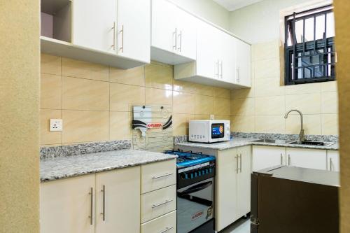 uma cozinha com armários brancos e um forno com placa de fogão em The Vacation Homes Apartments em Kigali