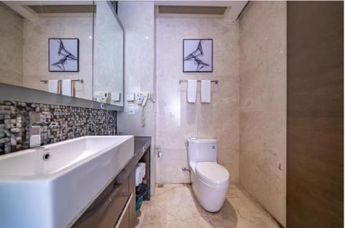 La salle de bains blanche est pourvue d'un lavabo et de toilettes. dans l'établissement Millenia Executive Apartment - Guangzhou East Railway Station Zhujiang New Town Branch, à Canton