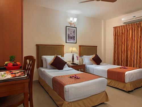 a hotel room with two beds and a table at MGM Vailankanni in Velankanni