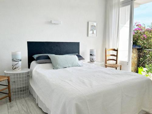 une chambre avec un grand lit blanc et deux chaises dans l'établissement Appartement lumineux avec terrasse, 500m de la plage, Bormes-les-Mimosas - FR-1-251-576, à Bormes-les-Mimosas