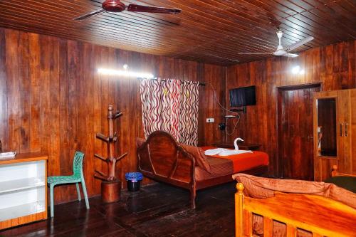 1 dormitorio con paredes de madera, 1 cama y 1 silla en Hill Valley Farm House, en Nelliyampathy