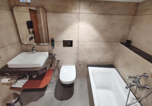 a bathroom with a sink and a toilet and a tub at Royal Plaza Suites by RAK Rooms, Mangaluru in Mangalore