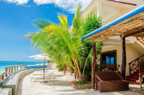 Blue Tides Hotel في نونغوي: منتجع على الشاطئ يوجد به نخل والمحيط