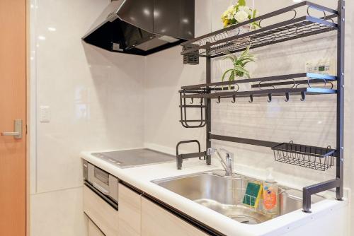 a kitchen with a sink and a shelf above it at 板橋駅前店・ダイヤモンド・悠 in Tokyo