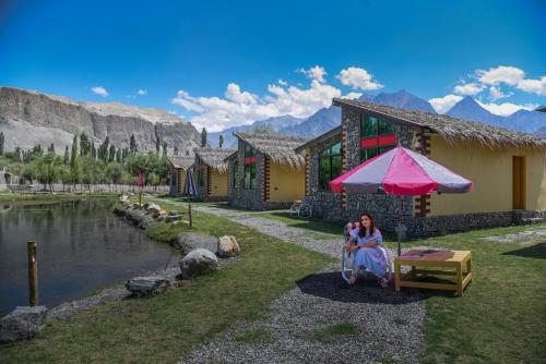 a woman sitting under an umbrella in front of a building at LOKAL Rooms x Skardu (Katpana Retreat) in Skardu