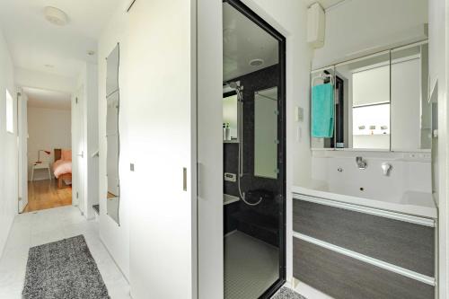 uma casa de banho com uma cabina de duche ao nível do chão e um espelho. em Pencil House - 10 mins walk to Shinjuku em Tóquio