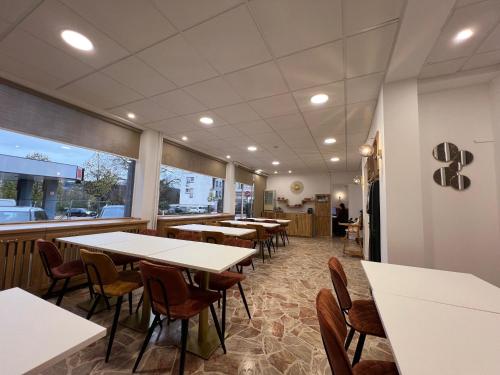 une salle à manger avec des tables et des chaises blanches dans l'établissement Contact Hôtel Foch, à Besançon