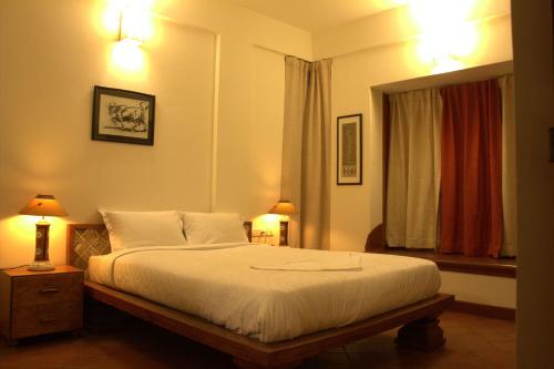 a bedroom with a bed and two lamps and a window at Nisargha Serviced Apartments in Bangalore