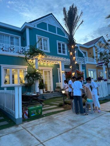 a group of people standing in front of a blue house at Novaworld Phan thiết - Alina house- 2 bed rooms in Bình Sum