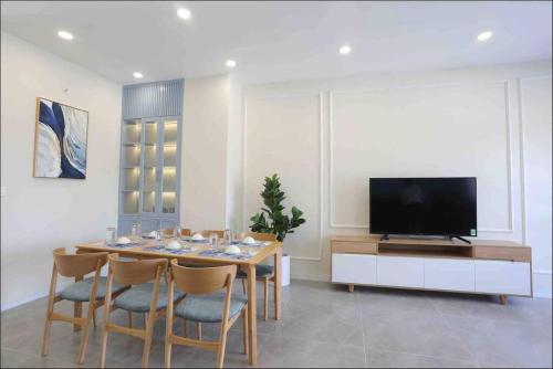 a dining room with a table with chairs and a television at Novaworld Phan thiết - Alina house- 2 bed rooms in Bình Sum