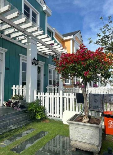 a house with a white fence and a plant with red flowers at Novaworld Phan thiết - Alina house- 2 bed rooms in Bình Sum