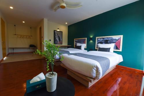 a bedroom with two beds and a green wall at LOKAL Rooms x Skardu (Katpana Retreat) in Skardu