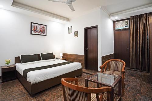 ein Schlafzimmer mit einem Bett, einem Stuhl und einem Tisch in der Unterkunft Hotel VM Residency in Neu-Delhi