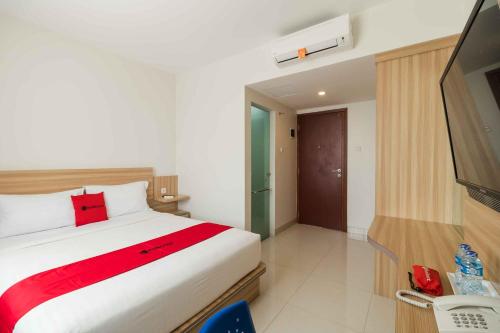 a hotel room with a bed and a television at RedDoorz at Homestay Lotus 2 Pangkal Pinang in Pangkalpinang