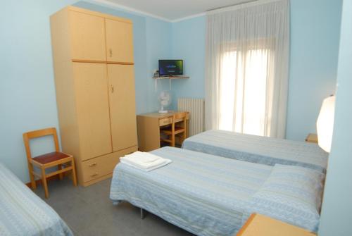 1 dormitorio con 2 camas, armario y silla en Hotel Del Duca, en Montedinove