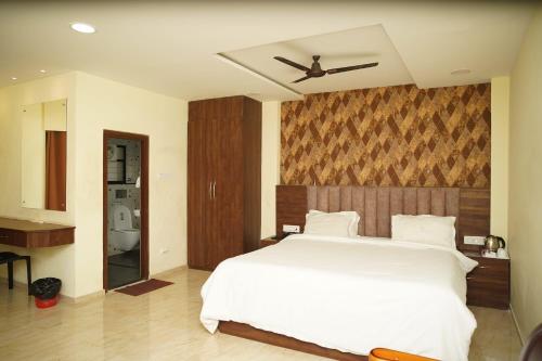 a bedroom with a white bed and a ceiling at VIRAMMA RESORT in Siliguri