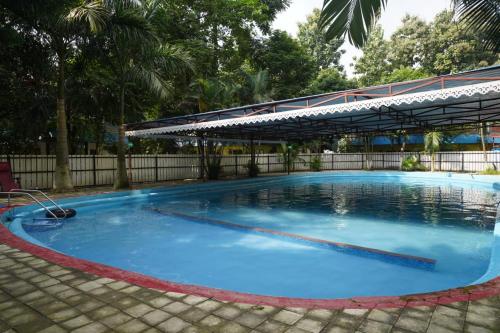 a large blue swimming pool with a canopy at VIRAMMA RESORT in Siliguri
