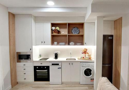 a kitchen with white cabinets and a washer and dryer at Cordvba Osario Centro in Córdoba