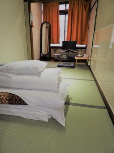 a room with white pillows and a desk with a computer at Yamamoto Ryokan in Fukuoka