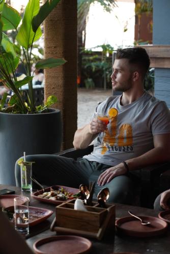 a man sitting at a table holding a drink at Red Thread Morjim in Morjim