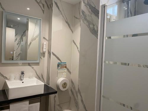 a white bathroom with a sink and a shower at Contact H&ocirc;tel Foch in Besan&ccedil;on