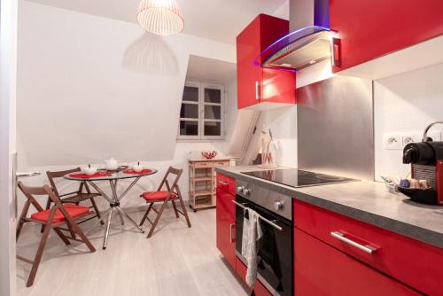 une cuisine avec des placards rouges et une table avec des chaises dans l'établissement La Loge by 