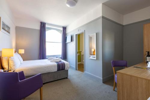 1 dormitorio con 1 cama, mesa y sillas en Dilkhusa Grand Hotel by Compass Hospitality en Ilfracombe