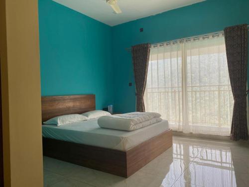 a bedroom with a bed with blue walls and windows at Earth Lounge Resort in Vagamon