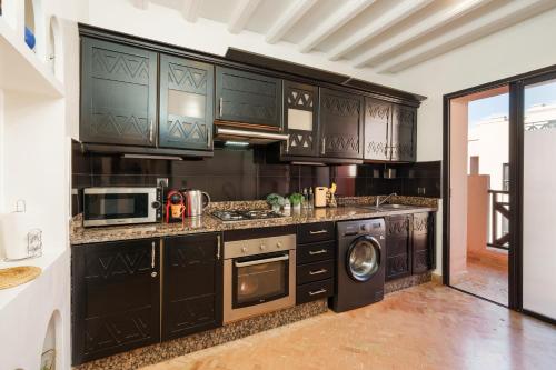 uma cozinha com armários pretos e uma máquina de lavar e secar roupa em Appartement aux portes de la palmeraie em Marraquexe