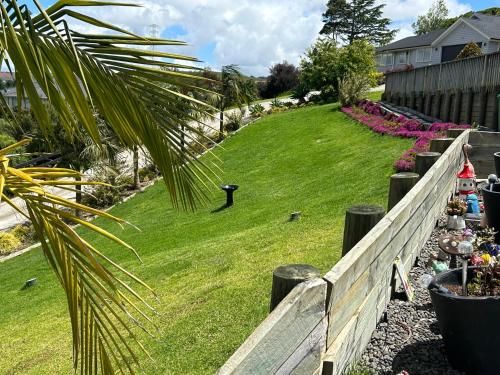 a yard with a fence and green grass and flowers at Cross Roads in Pokeno