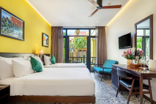 a hotel room with two beds and a desk at Villa Soleil Hoi An in Hoi An
