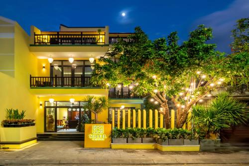 a yellow building with a fence and a tree at Villa Soleil Hoi An in Hoi An