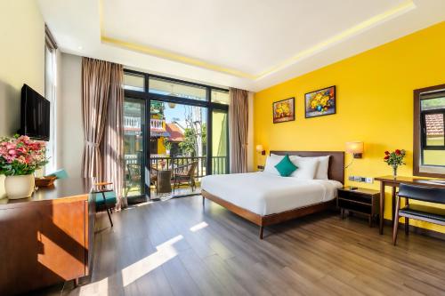 een hotelkamer met een bed en een bureau met een computer bij Villa Soleil Hoi An in Hội An