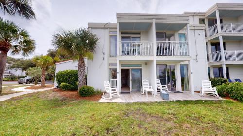a house with white chairs and palm trees at VILLA 315 - The Eagles Nest condo in Jekyll Island
