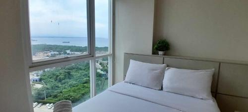 a bedroom with a white bed and a large window at Mactan Newtown Boulevard by FJCIVO in Lapu Lapu City
