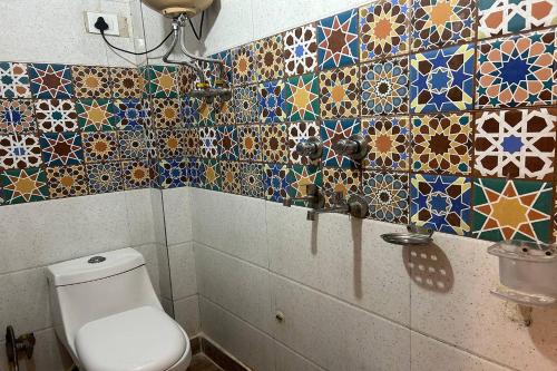 uma casa de banho com WC e azulejos coloridos na parede em Shree Lodge em Nova Deli