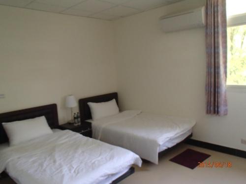 a bedroom with two beds and a window at 成功民宿 KM Bed and Breakfast in Jinhu