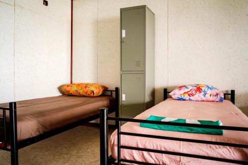 Habitación con 2 camas y armario en Havae Lodge, en Teahupoo