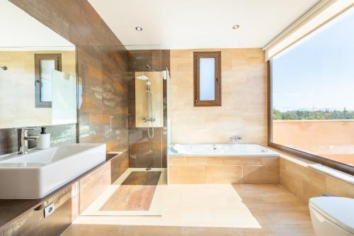 baño con lavabo, bañera y ventana en Finca Es Niu, en Santa Eugènia