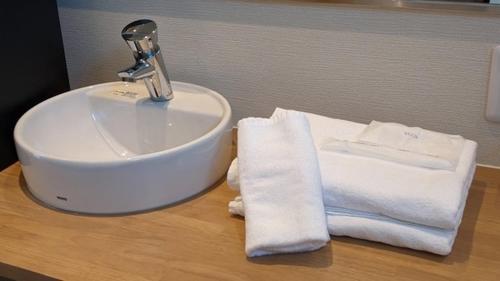 関空国際ホテル في واكاياما: حوض الحمام والمناشف على كونتر خشبي