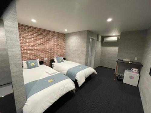 een kamer met 2 bedden en een bakstenen muur bij 関空国際ホテル in Wakayama