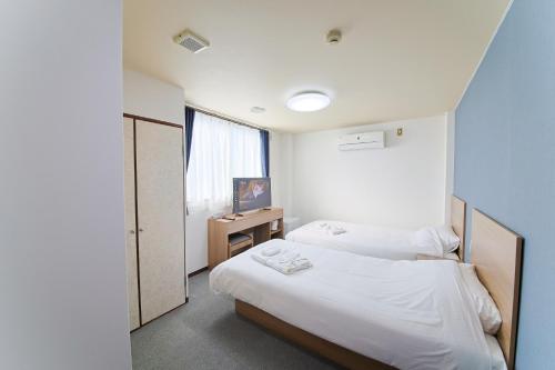 a bedroom with two beds and a window at ホテルよしや in Osaka