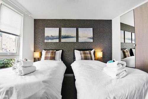 Dos camas en un dormitorio con toallas. en Thistle Apartments - King's Apartment, en Aberdeen