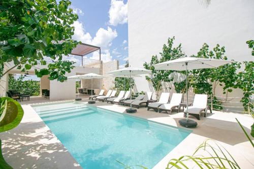 a swimming pool with chairs and umbrellas at Akumal Bay With Access To The Beach 7 Rooftop Pools in Akumal